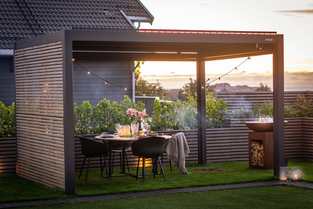 Pergola bioclimatique PERGOLUX avec lames fermées sous une pluie bretonne, terrasse sèche et éclairée en automne