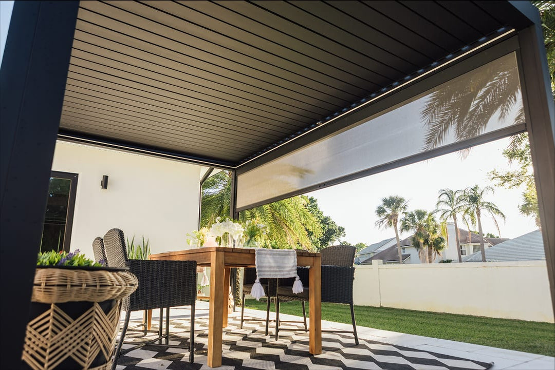 Terrasse française avec pergola bioclimatique à lames orientables ouverte sous soleil d'hiver, famille autour d'une table