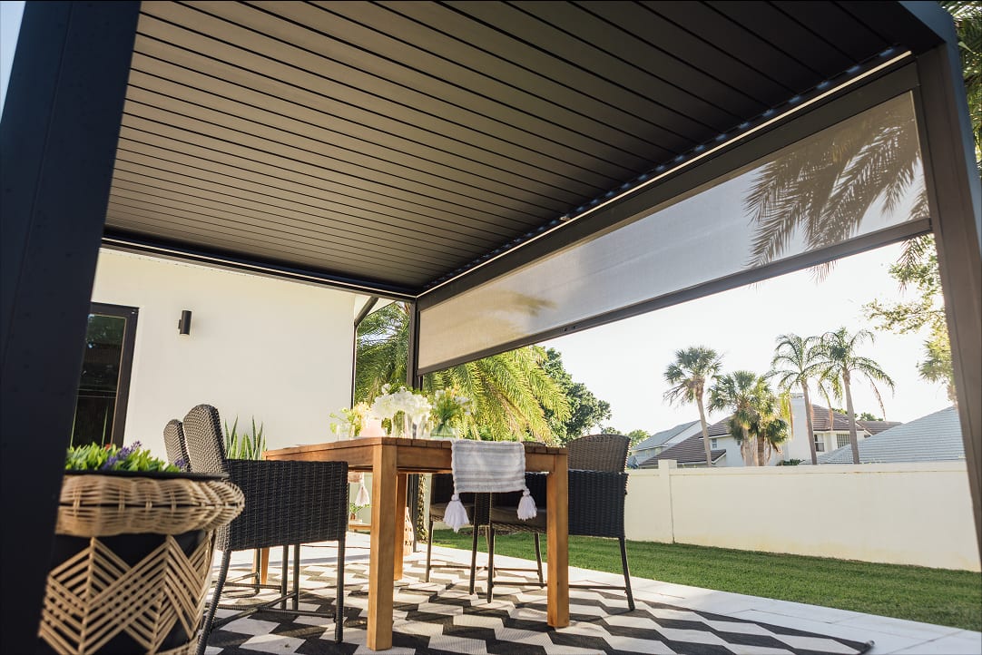 Terrasse française avec pergola bioclimatique à lames orientables ouverte sous soleil d'hiver, famille autour d'une table