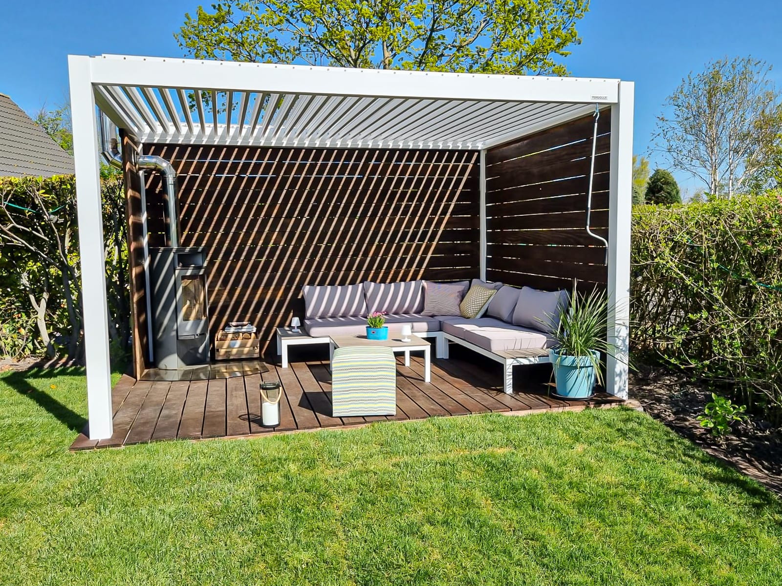 Terrasse française avec pergola bioclimatique ouverte, table de 6 couverts et chaises reculées, lumière d'été en fin d'après-midi