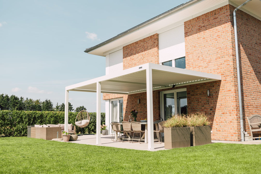 Propriétaire mesurant une terrasse carrelée avec un mètre ruban, maison avec façade claire en arrière-plan, journée ensoleillée
