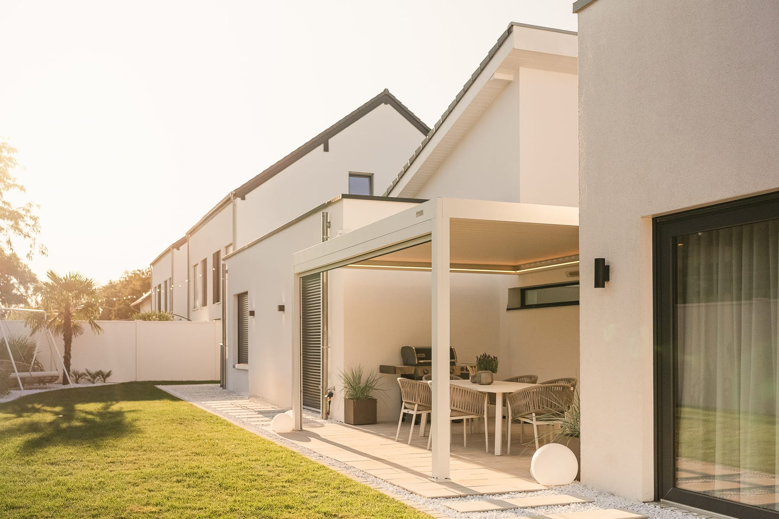 Pergola à lames orientables aluminium sur terrasse française, lames mi-ouvertes laissant entrer la lumière rasante du soir